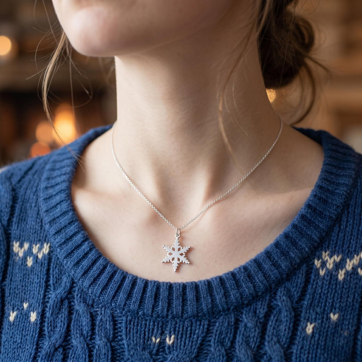 Silver-tone snowflake pendant on thin chain, worn at the neckline