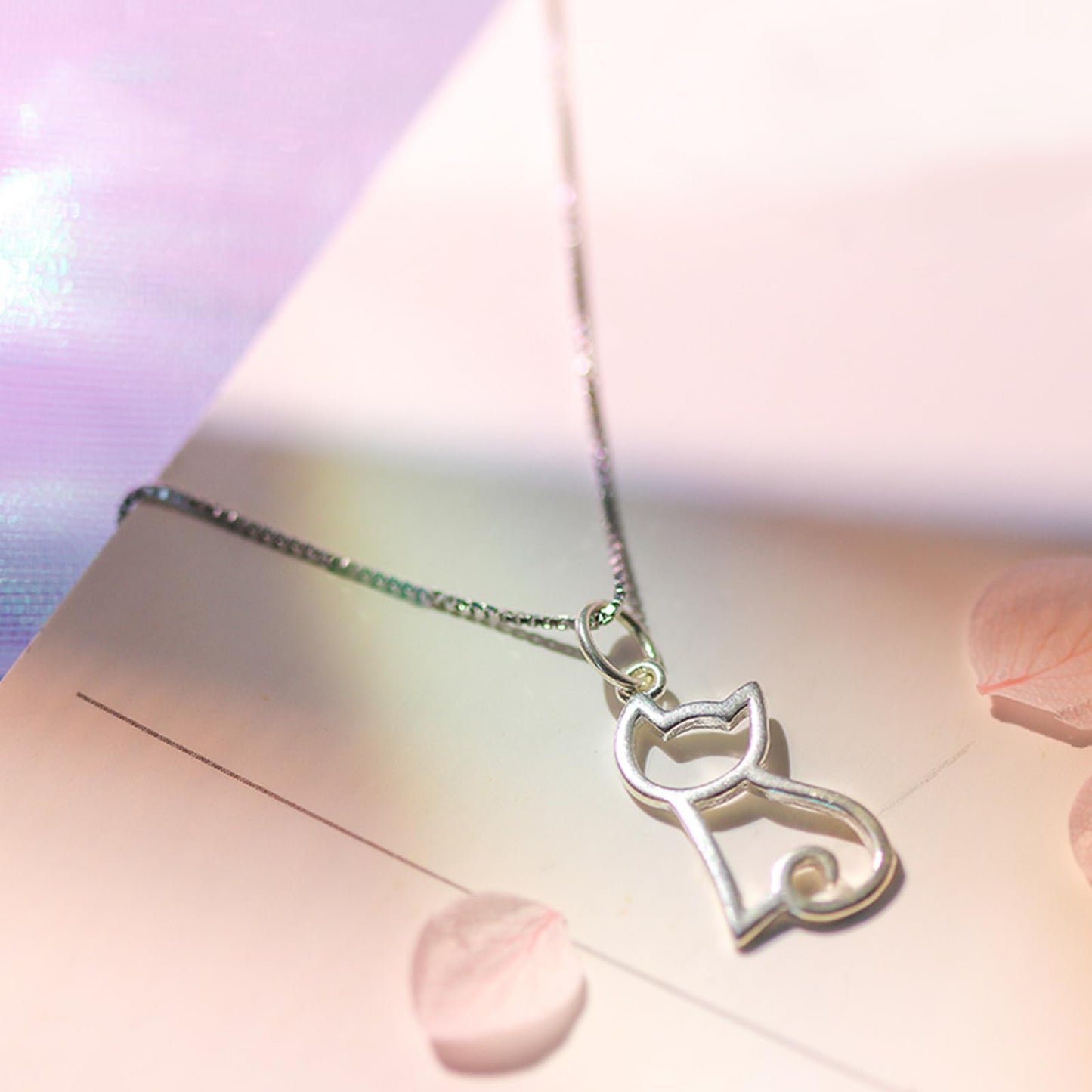 Silver-tone hollow kitten charm pendant on a delicate chain, close-up with loop bail.
