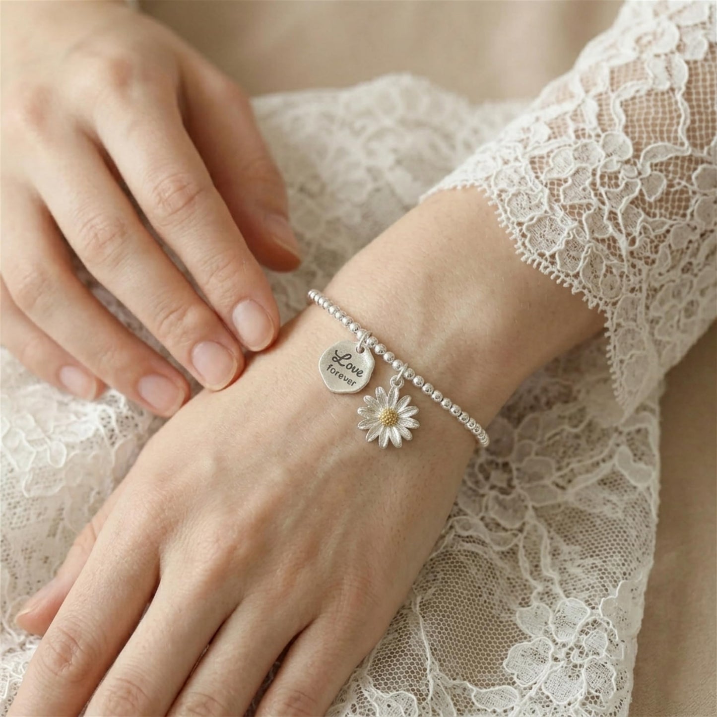 Silver charm bracelet with “Love forever” heart and small daisy detail on wrist