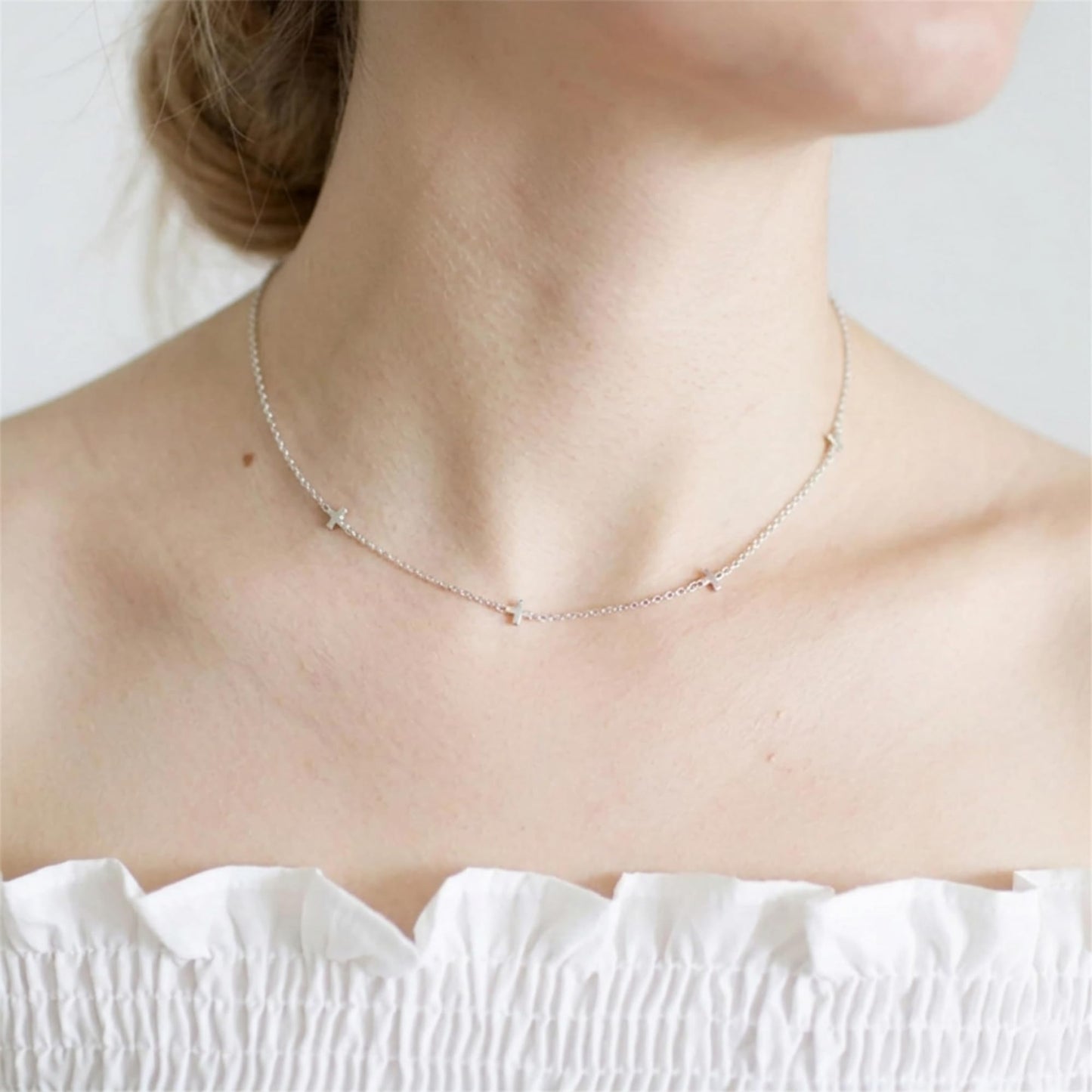 Silver-tone mini cross charm necklace worn at the neck, small cross pendants