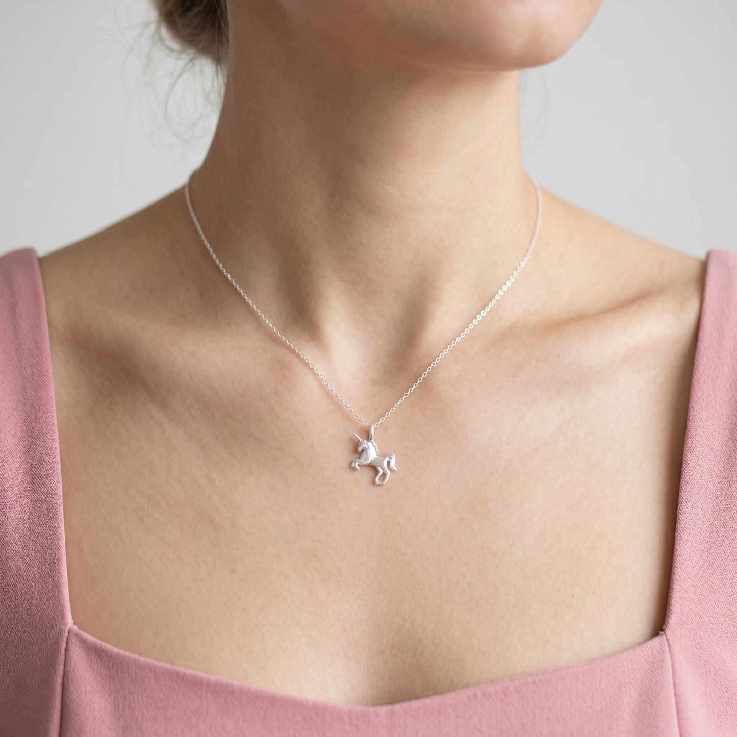 Unicorn charm necklace worn on neckline, silver chain with unicorn pendant