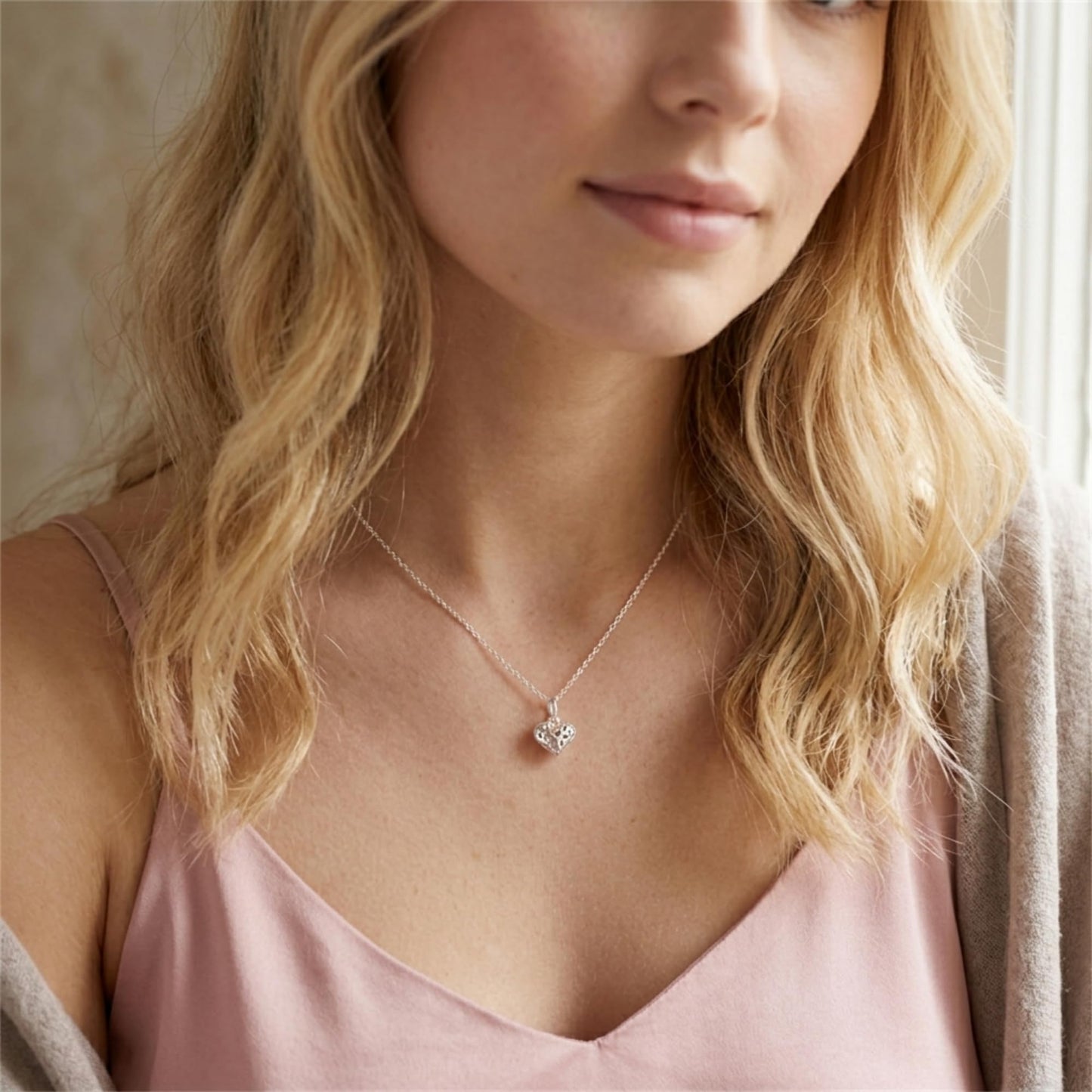 Silver heart pendant necklace worn on a blonde model with a pink dress