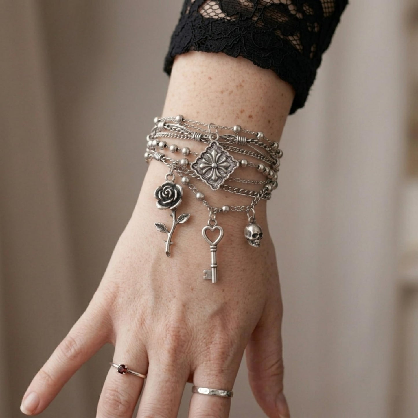 Fleur-de-lis charm pendant on silver-tone bracelet with rose, heart, and key charms