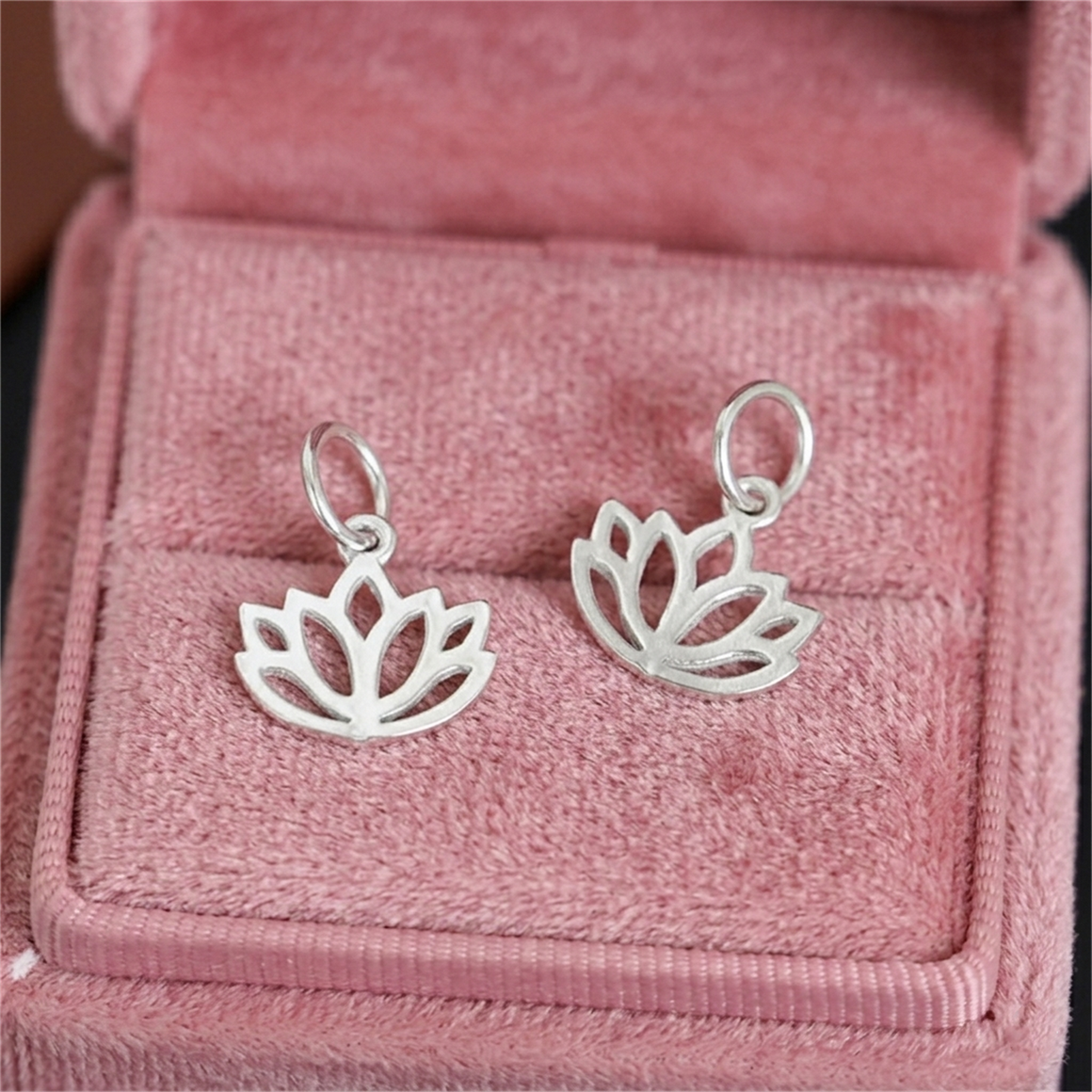 Two silver-toned filigree lotus charm pendants with oval hanging loops