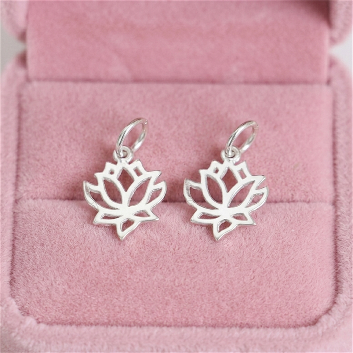 Two filigree lotus charm pendants, silver-toned, with hinged-style hanging loops