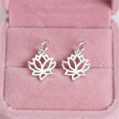 Two filigree lotus charm pendants, silver-toned, with hinged-style hanging loops