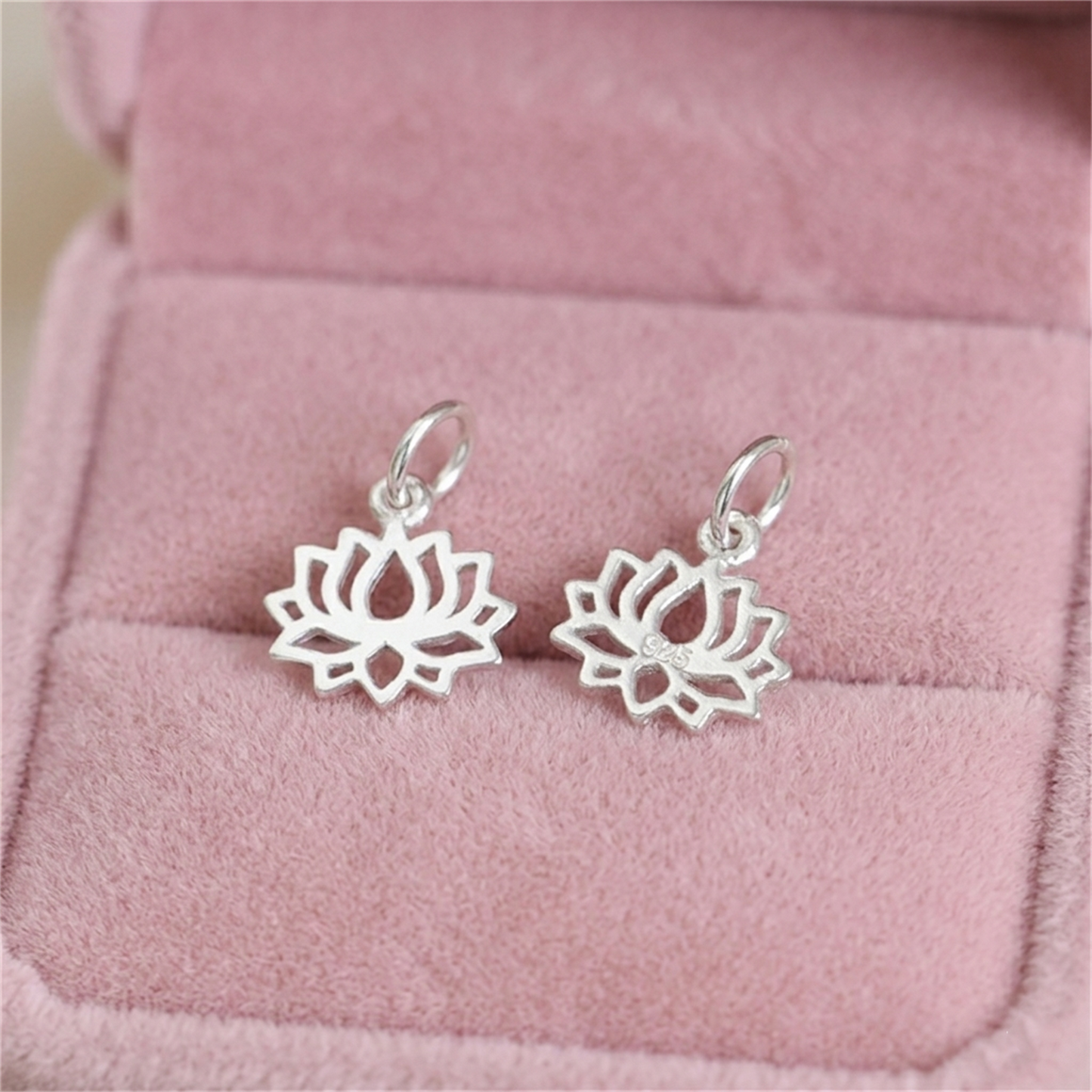 Pair of filigree lotus charm pendants, silver-toned, hanging from small rings