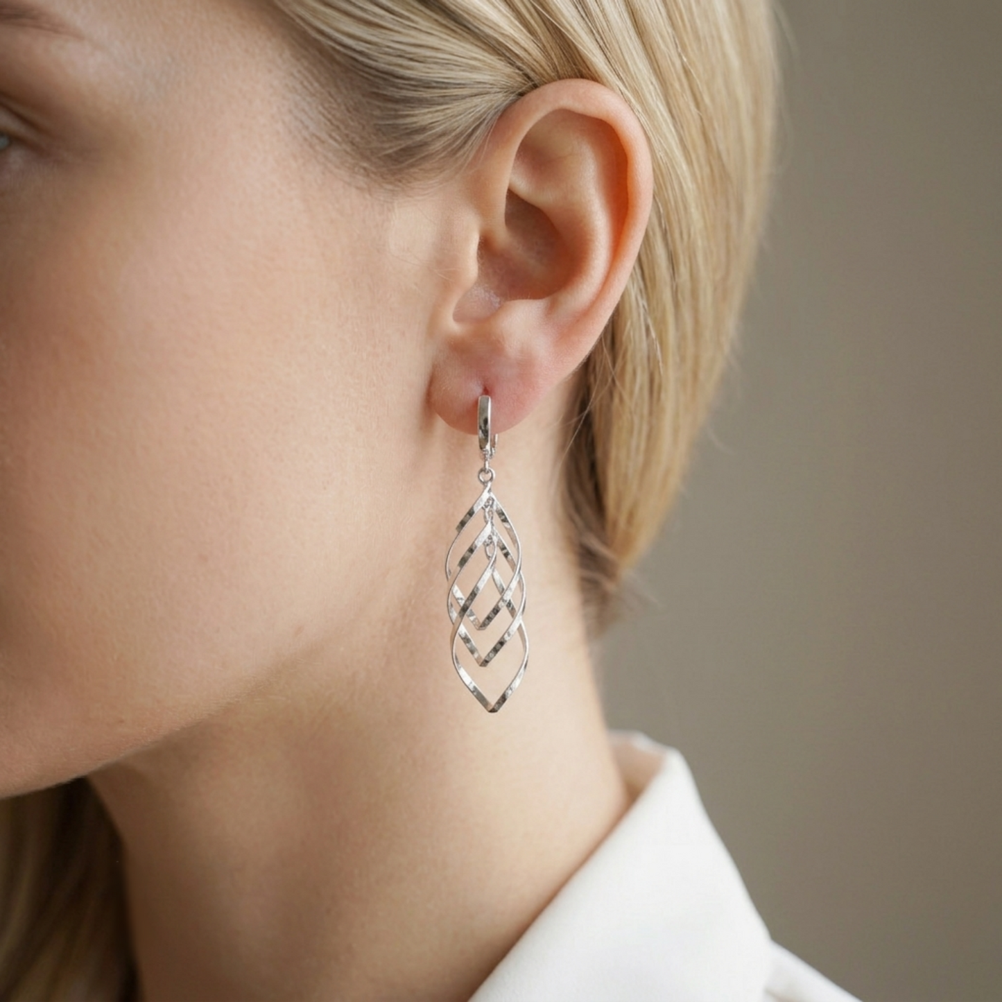 Dangly silver-tone hoop earrings with diamond lattice drop, worn on ear