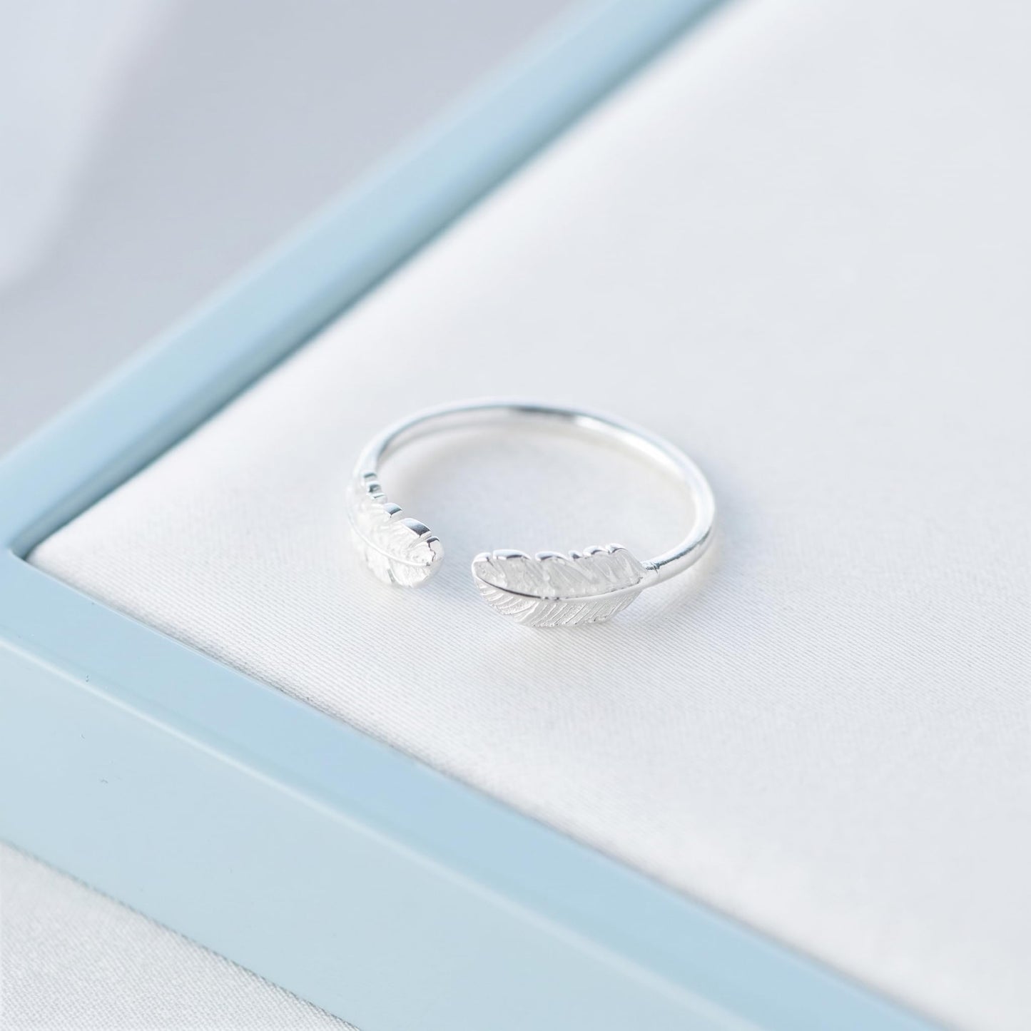 Silvertone open band ring with two small feather wings, curved for finger fit
