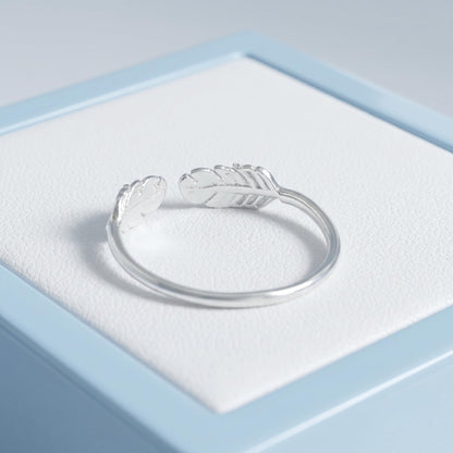 Open band ring laying flat, two feather-wing emblems on the band