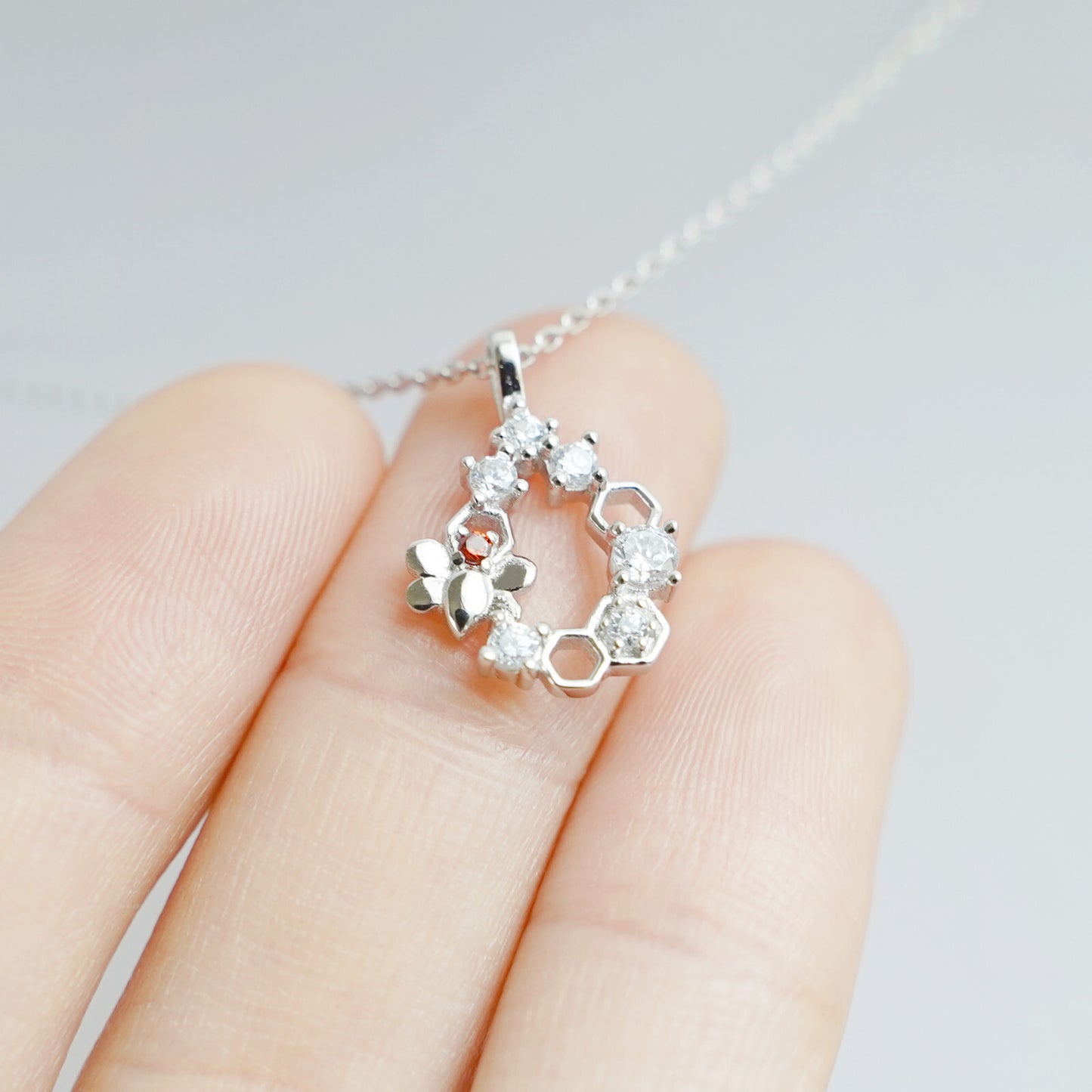 Honeycomb necklace charm with bee detail and hexagon stones, close-up