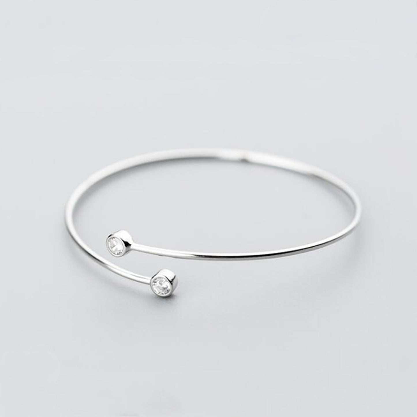 Silver-tone torque bangle with two round CZ stones spaced on the bar