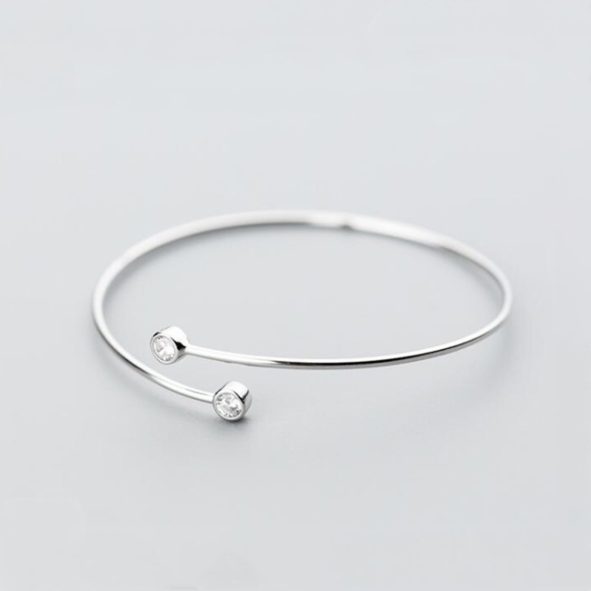 Silver-tone torque bangle with two round CZ stones spaced on the bar