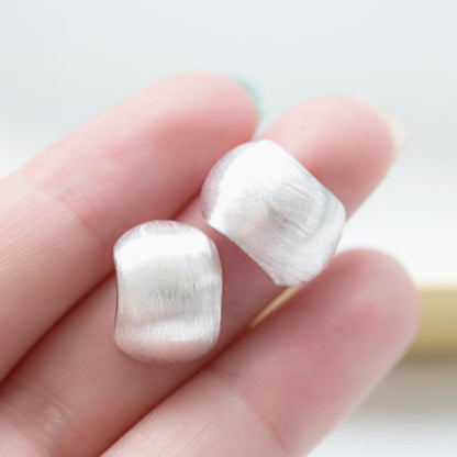 Brushed metal half-hoop drops in hand, curved silver finish