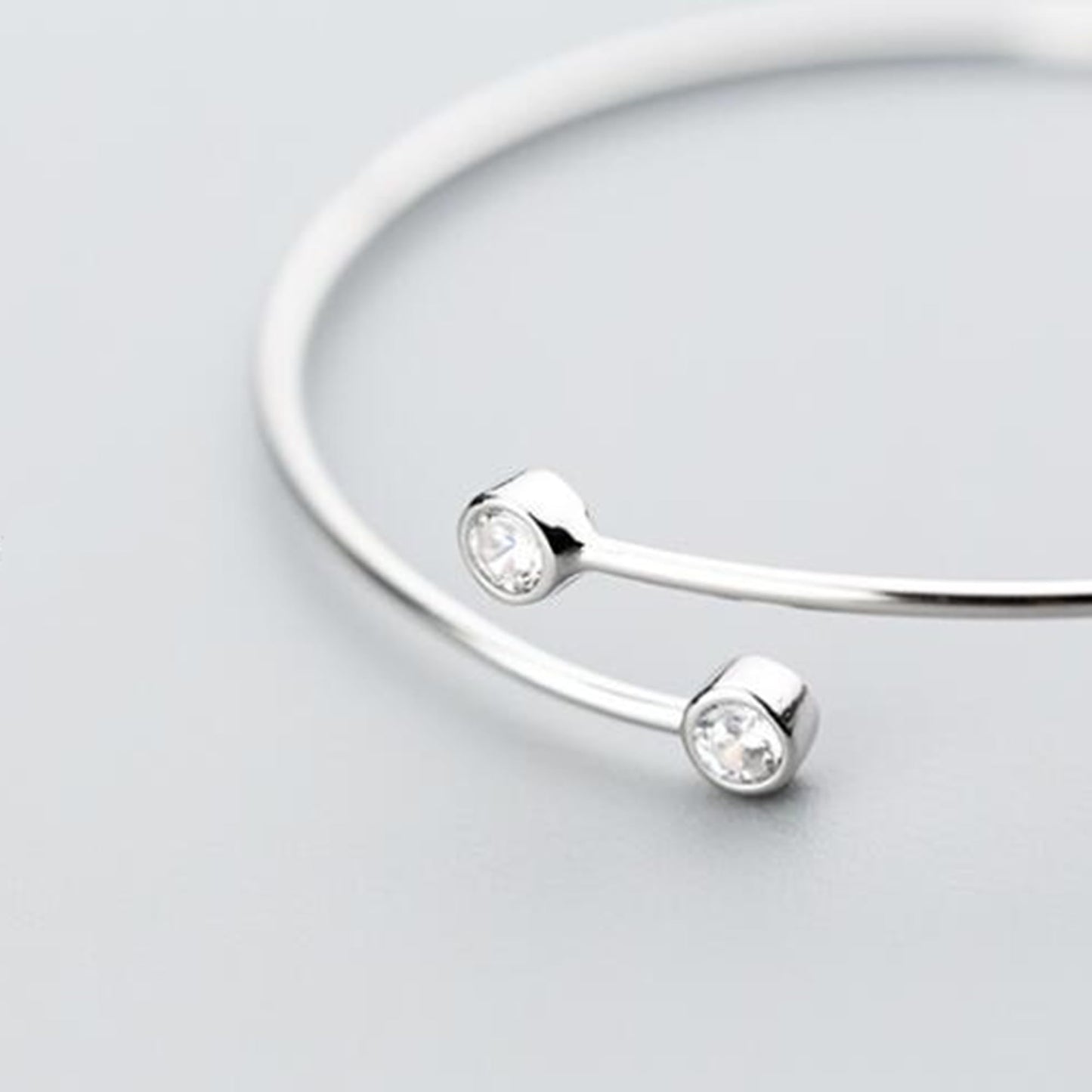 Close-up: CZ torque bangle with two round stones on curved wire band