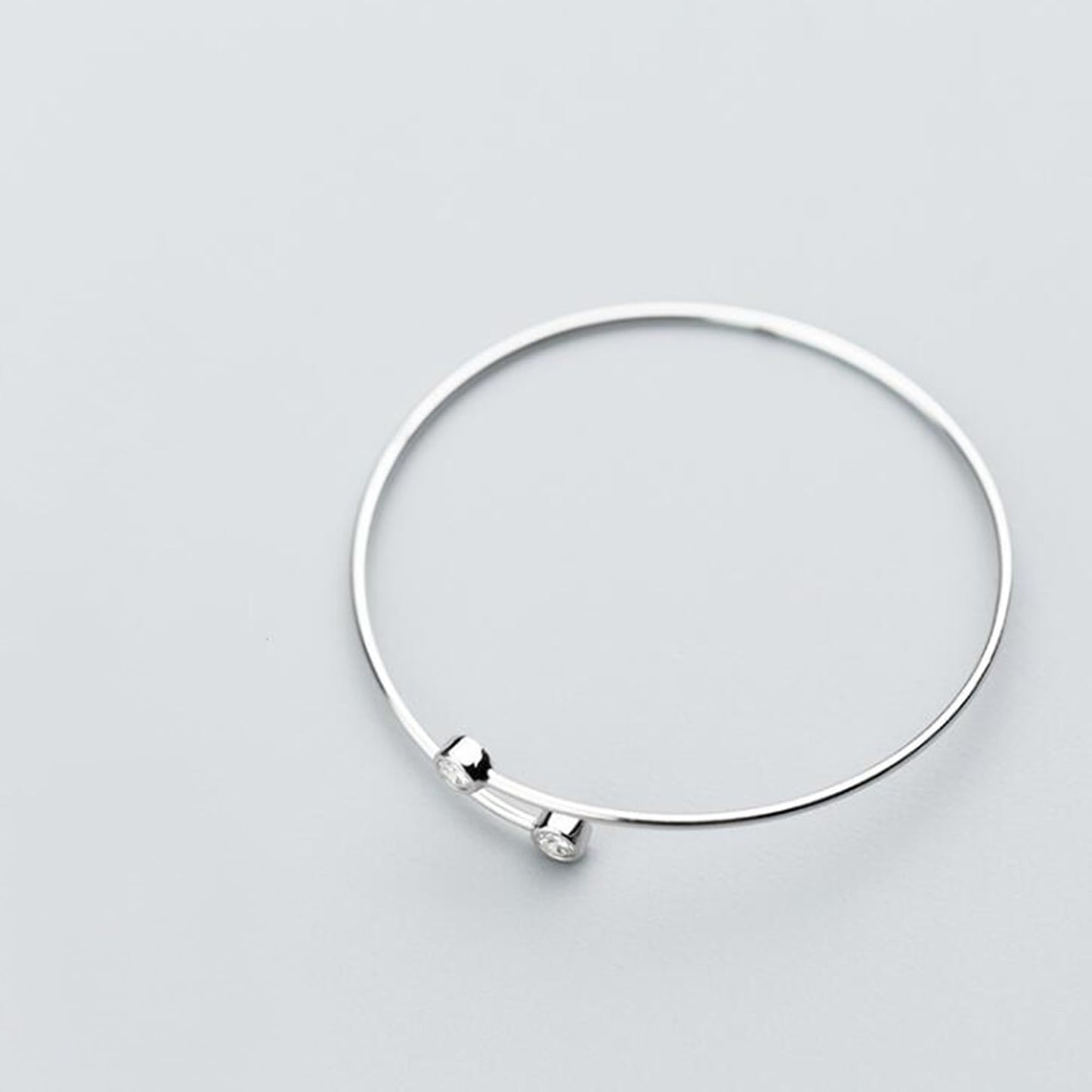 Silver CZ torque bangle with two small round bezel-set stones