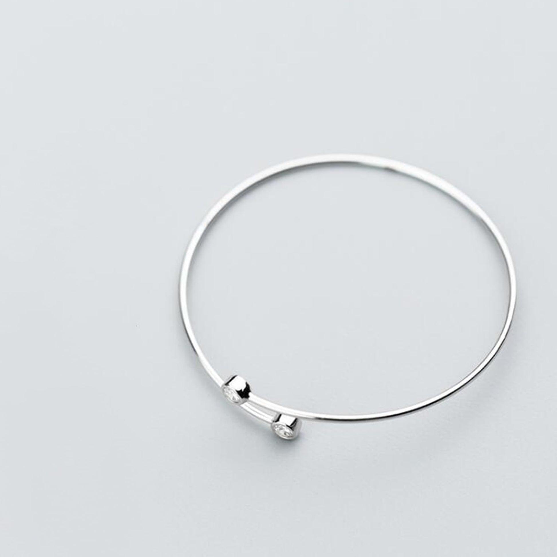 Silver CZ torque bangle with two small round bezel-set stones
