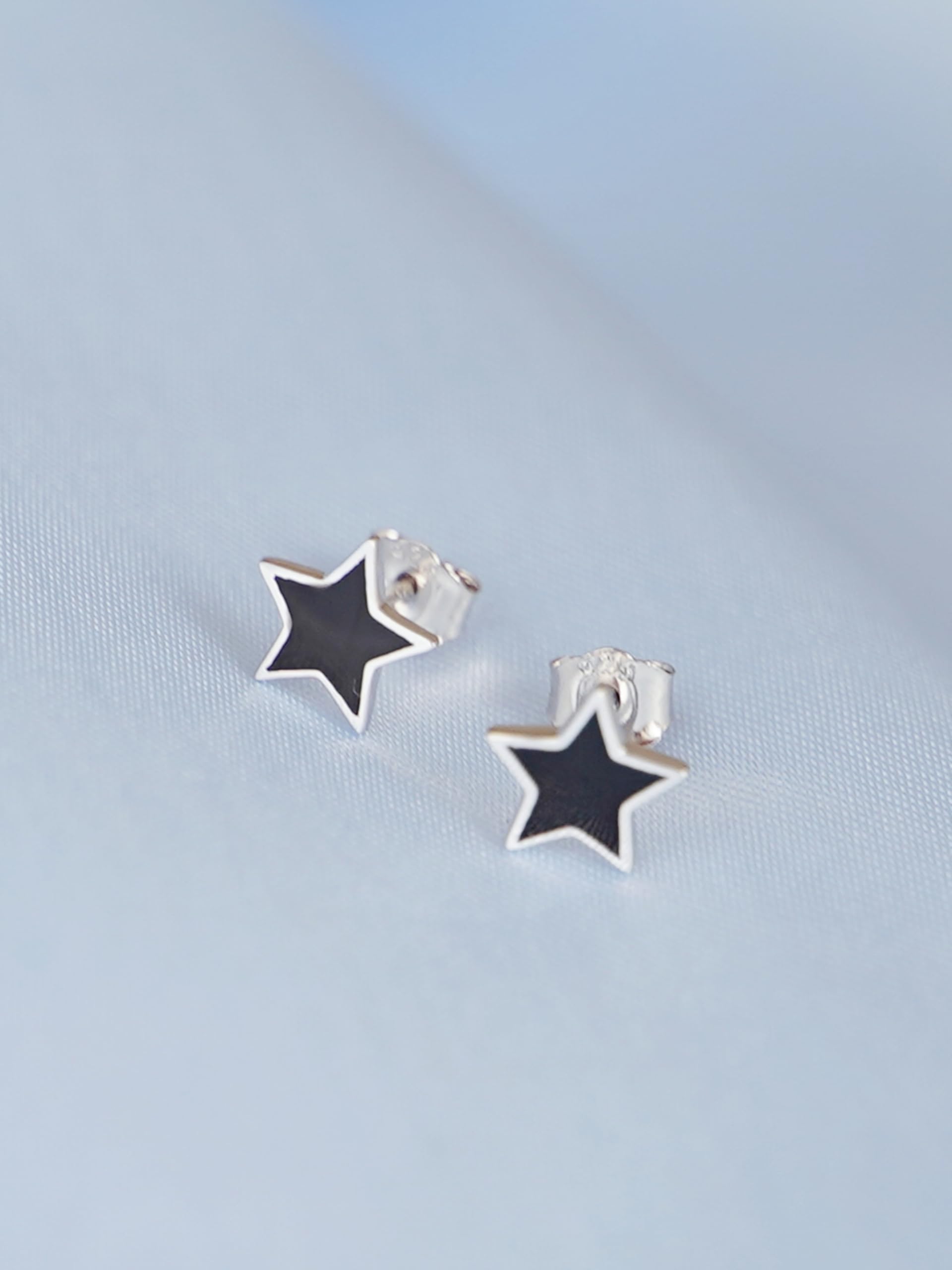 Black star studs with silver back, close-up of black enamel and metal post