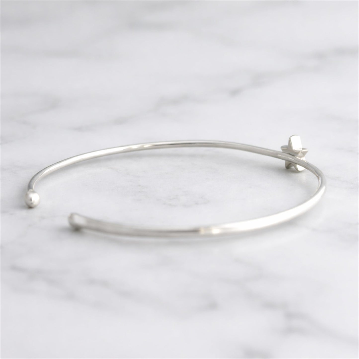 Silver-tone star torque bangle bracelet from side angle with star charm
