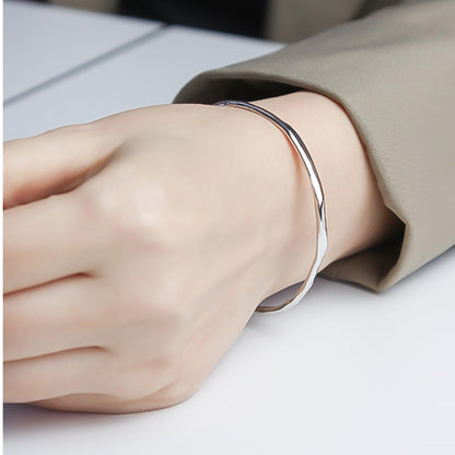 Hammered rhodium silver cuff bracelet worn on wrist, shiny curved band