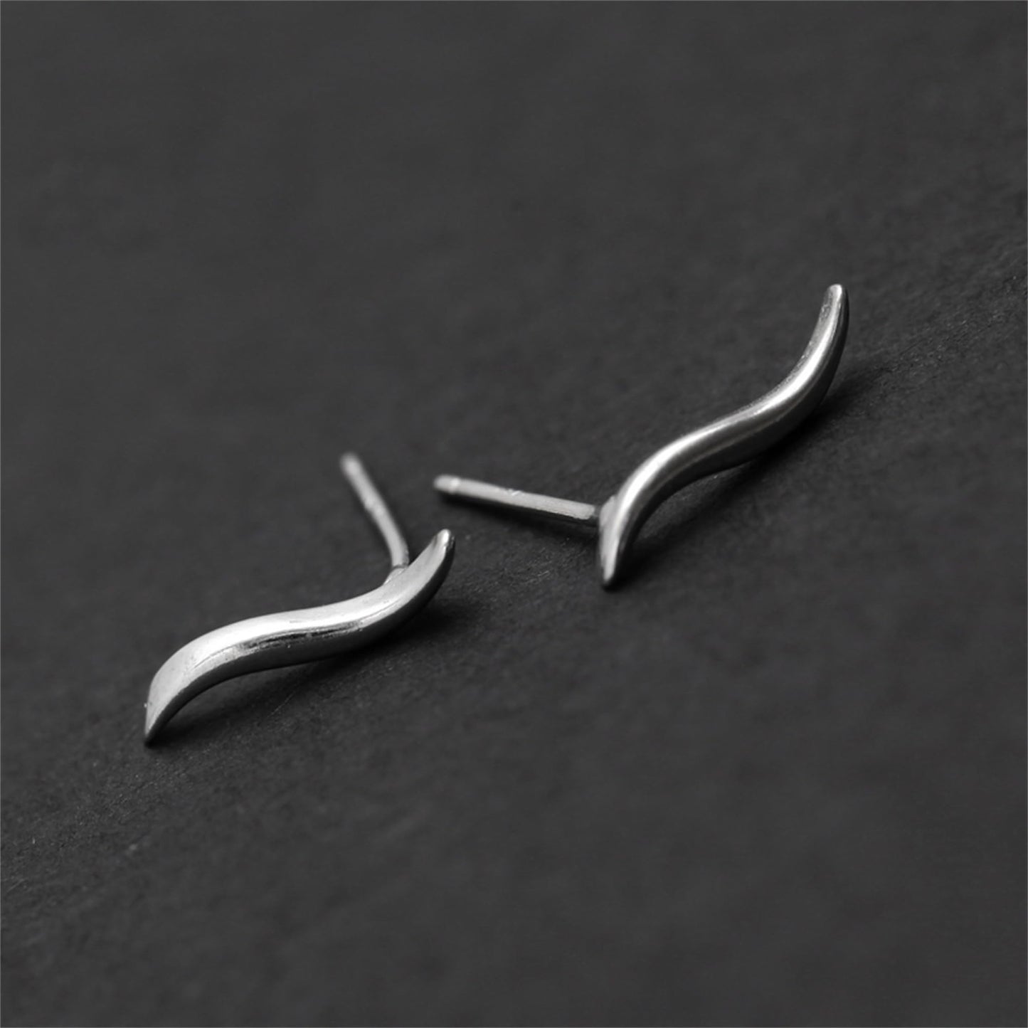 Wavy vine climber stud earrings, angled view of curved metal wave and earring post