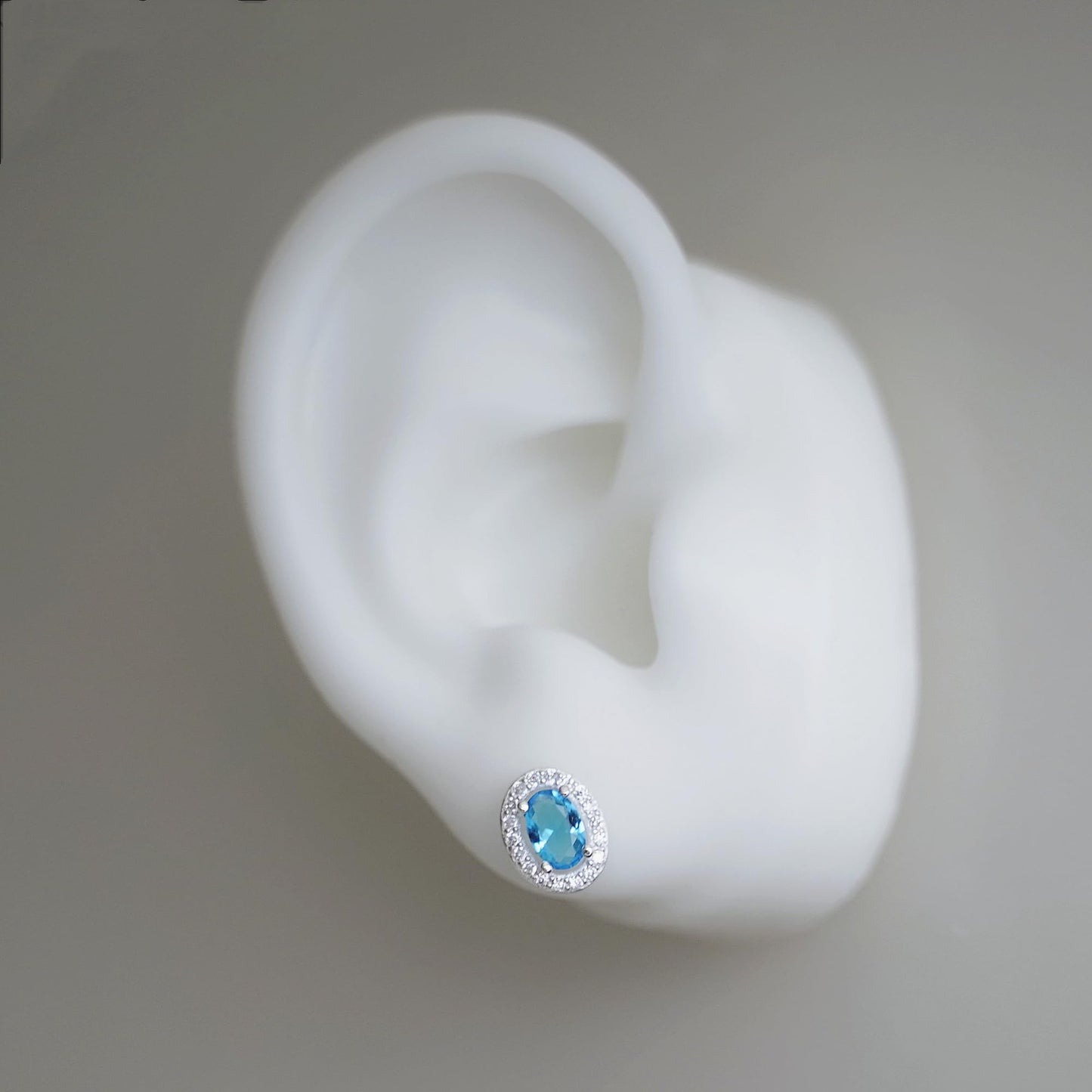 Single blue oval CZ halo stud earring in a silver-tone setting