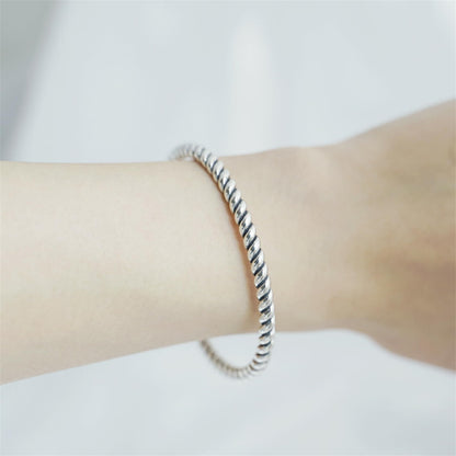Pearl Twisted Torque Bangle worn on wrist, twisted silver cuff with pearl drop