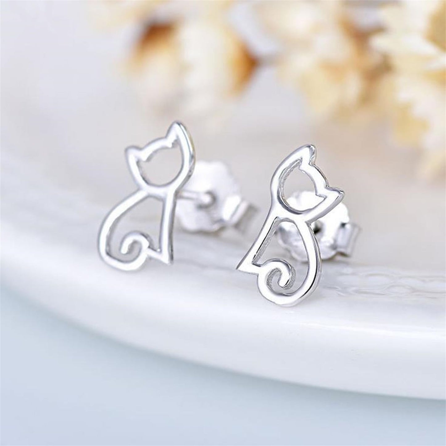 Close-up of cat outline stud earrings, polished silver cat silhouette