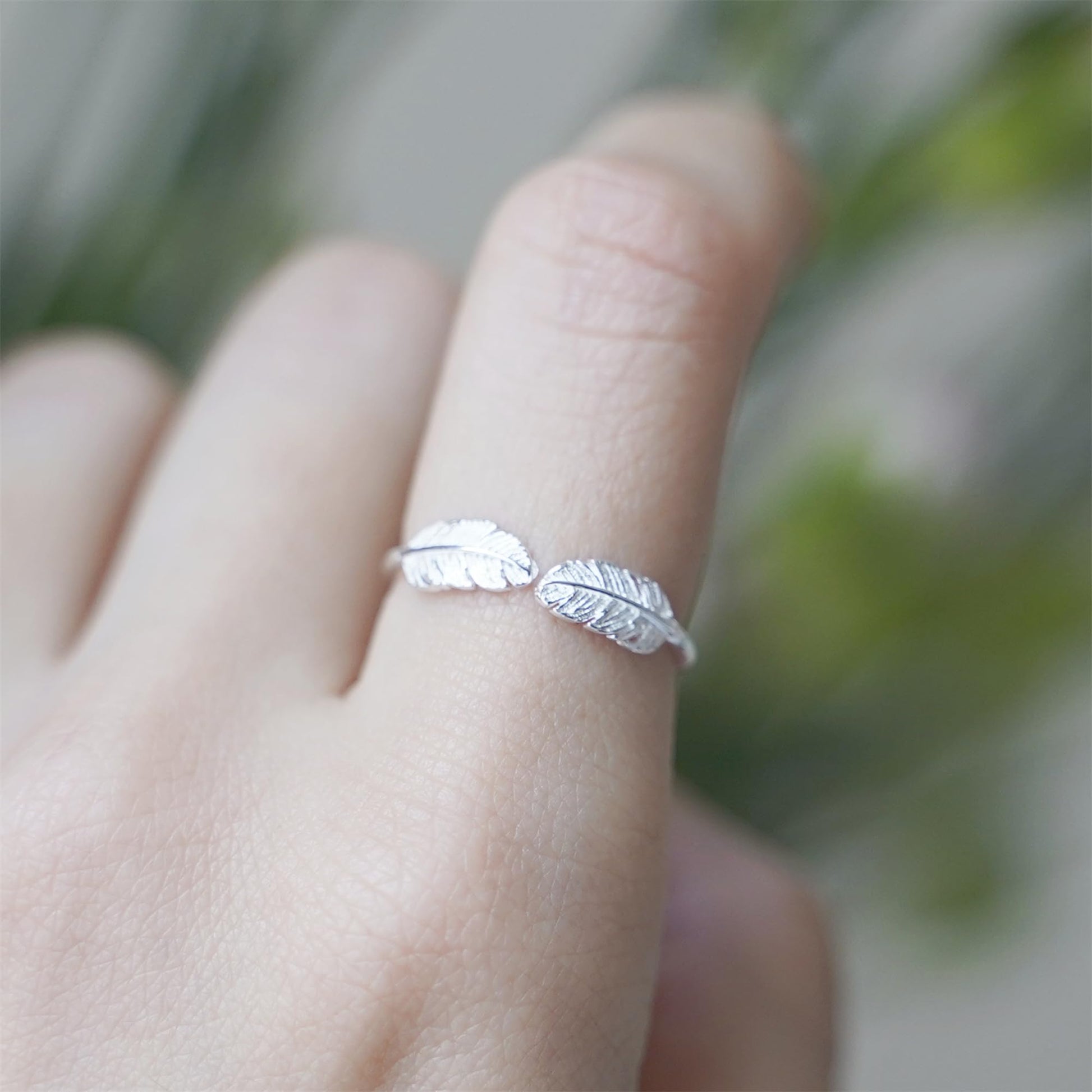 Double feather-wing open ring on finger, silvertone polished metal band