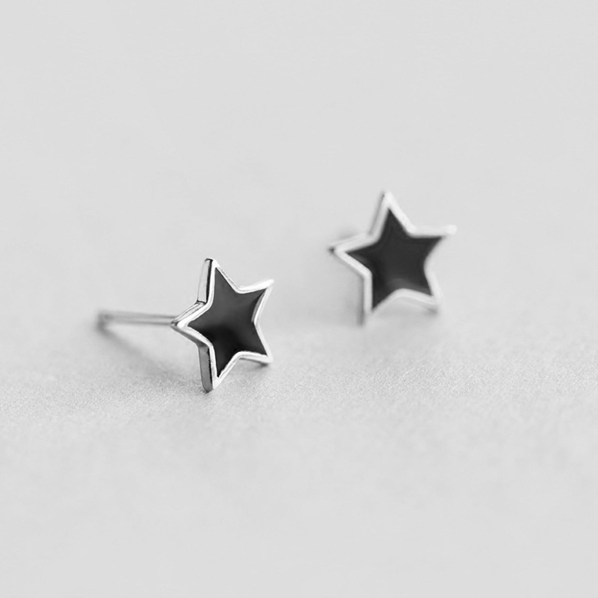 Black star stud earrings with silver posts extending from the back