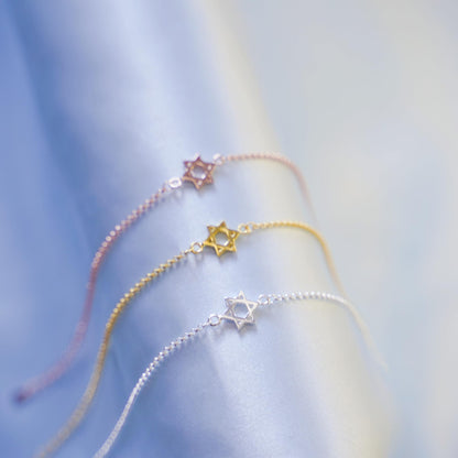 Star of David bracelets in rose, gold, and silver with star charms on chains.