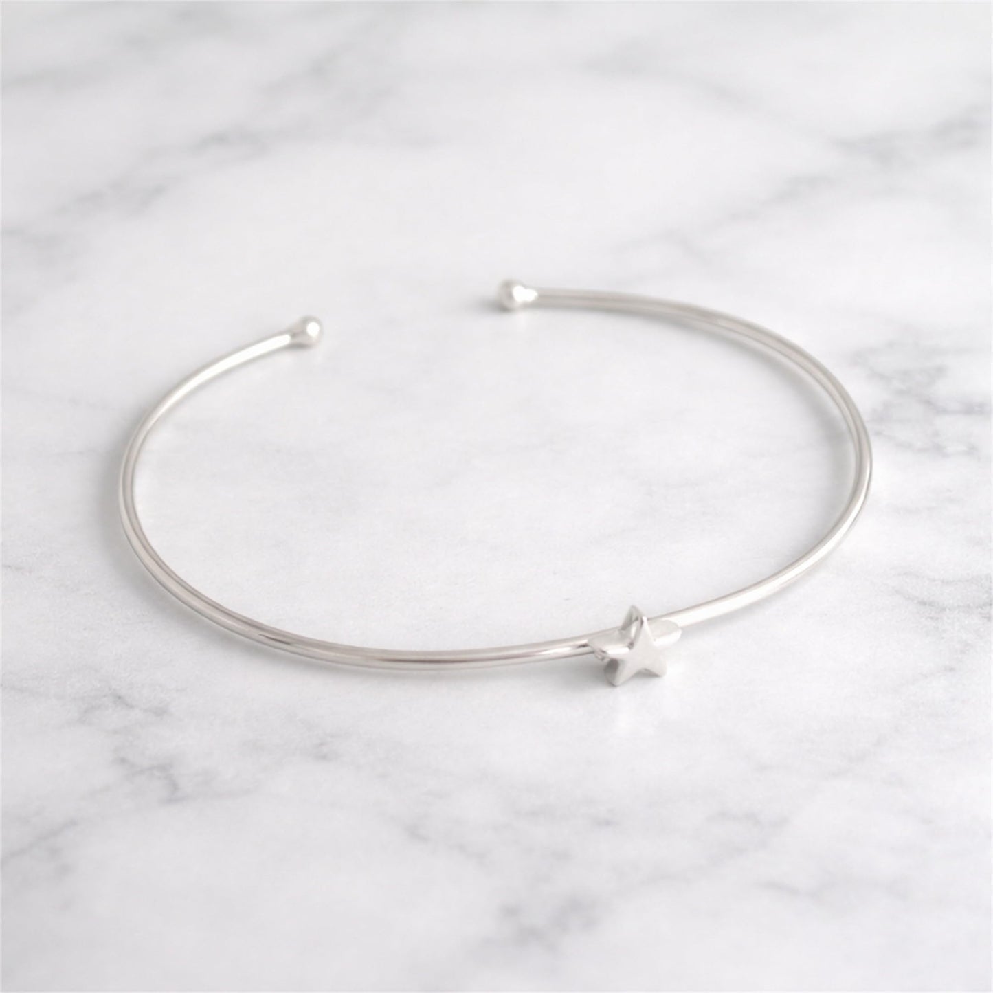 Star Bead Torque Bangle laid flat, silver-tone wire with star bead