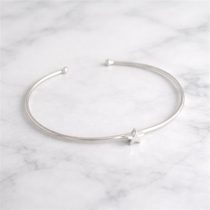 Star Bead Torque Bangle laid flat, silver-tone wire with star bead