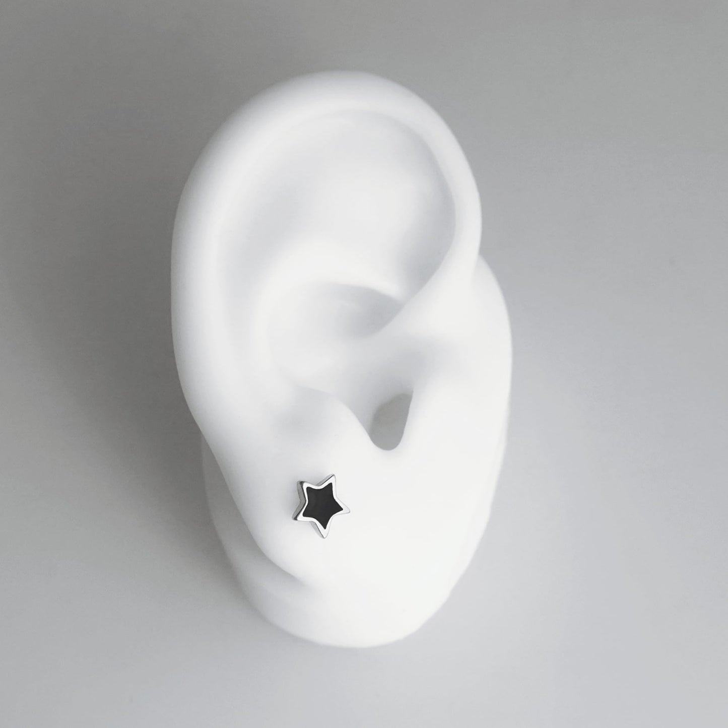 Side view of black star stud earring on a silver post