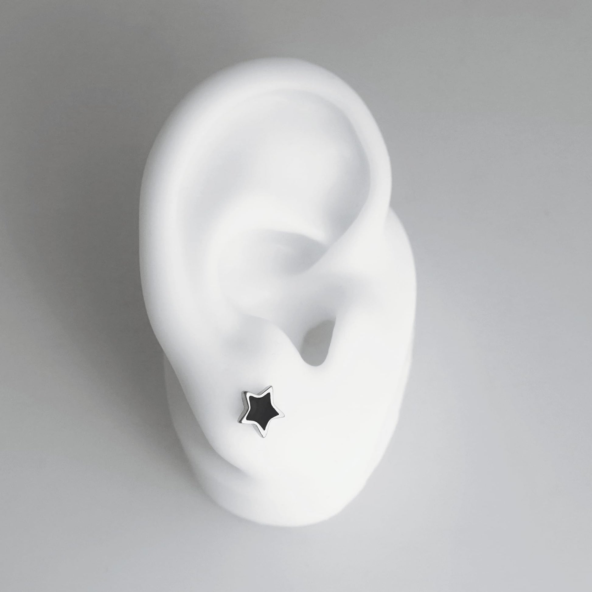 Side view of black star stud earring on a silver post