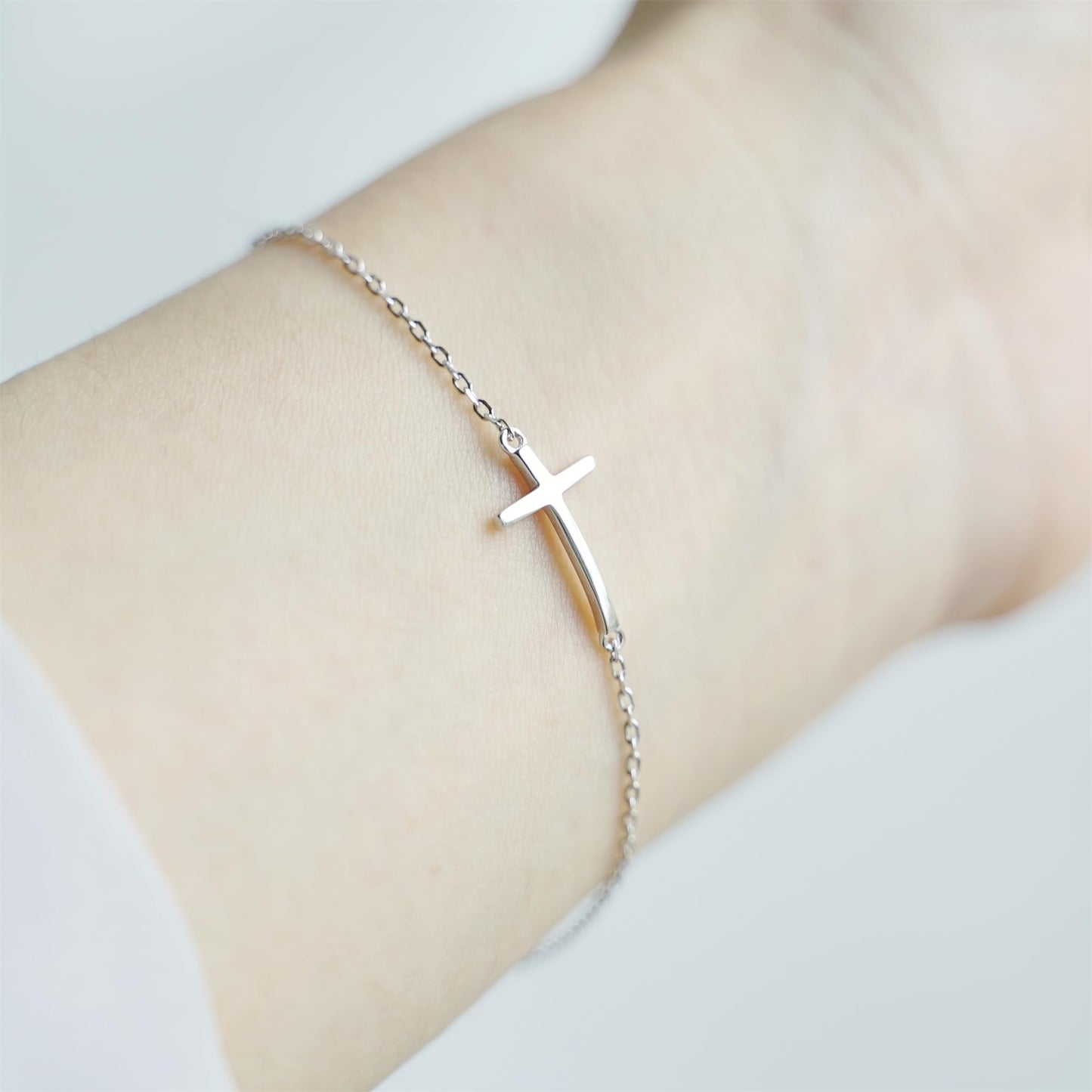 Sideways Cross anklet on wrist with silver-toned chain and cross charm