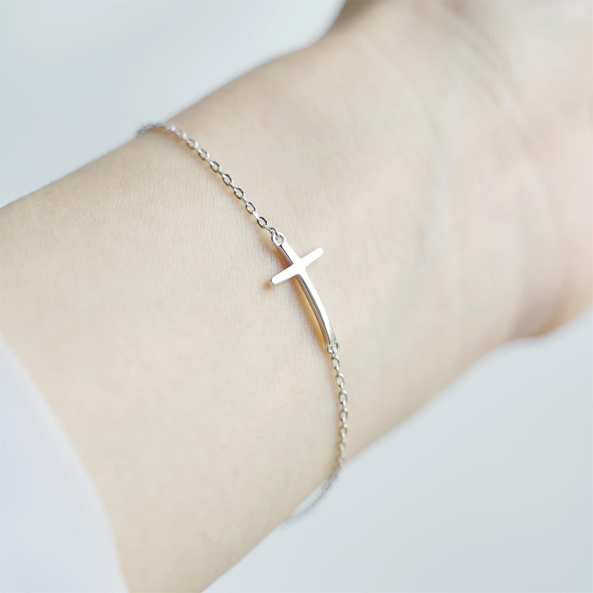 Sideways Cross anklet on wrist with silver-toned chain and cross charm