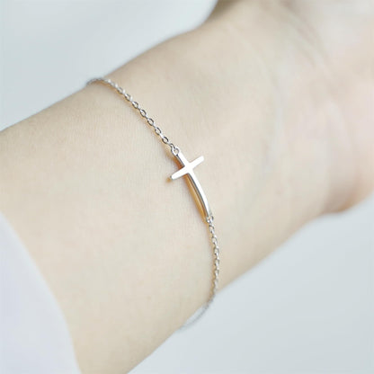 Sideways Cross anklet on wrist with silver-toned chain and cross charm