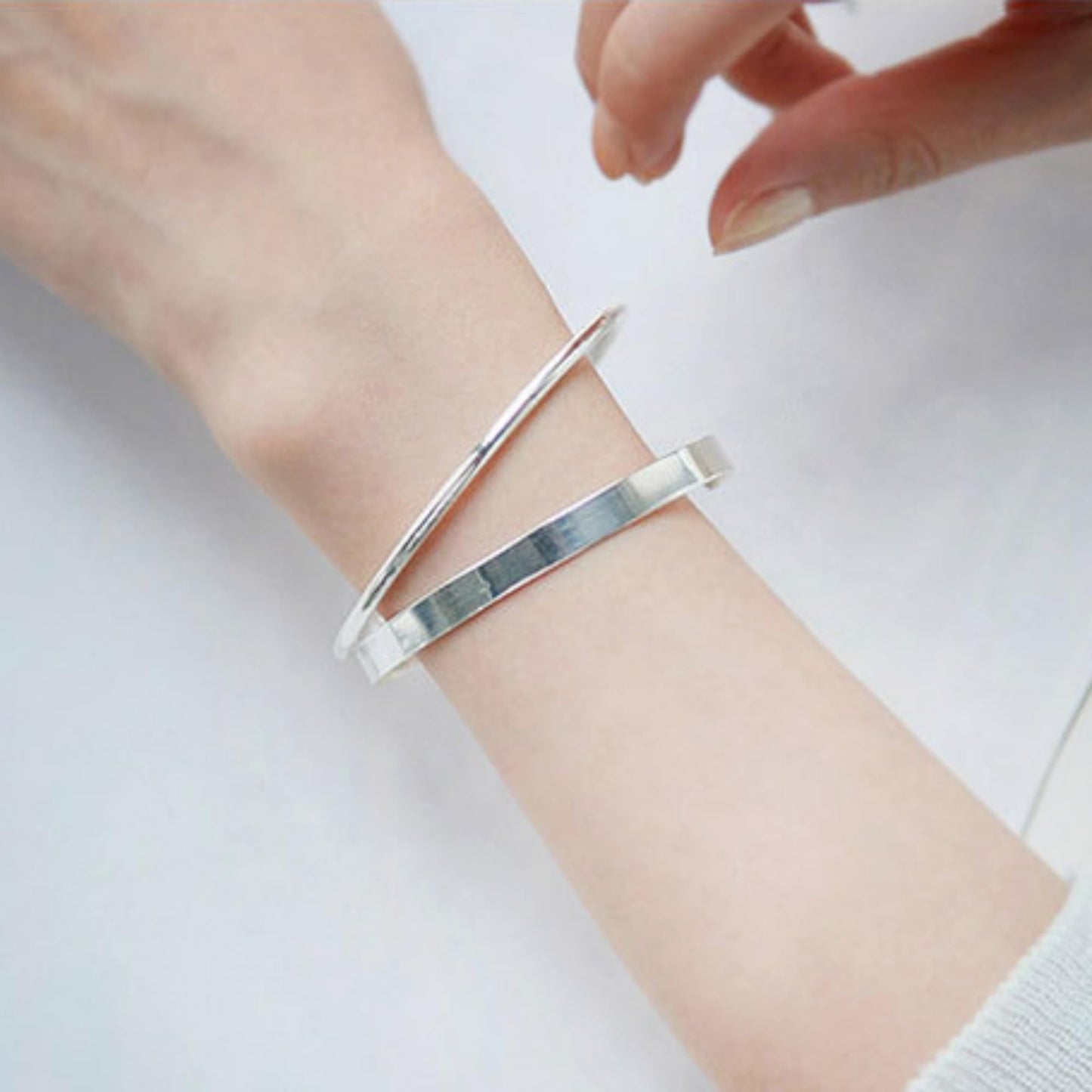 Polished cuff bangle on wrist with open cuff gap and reflective finish