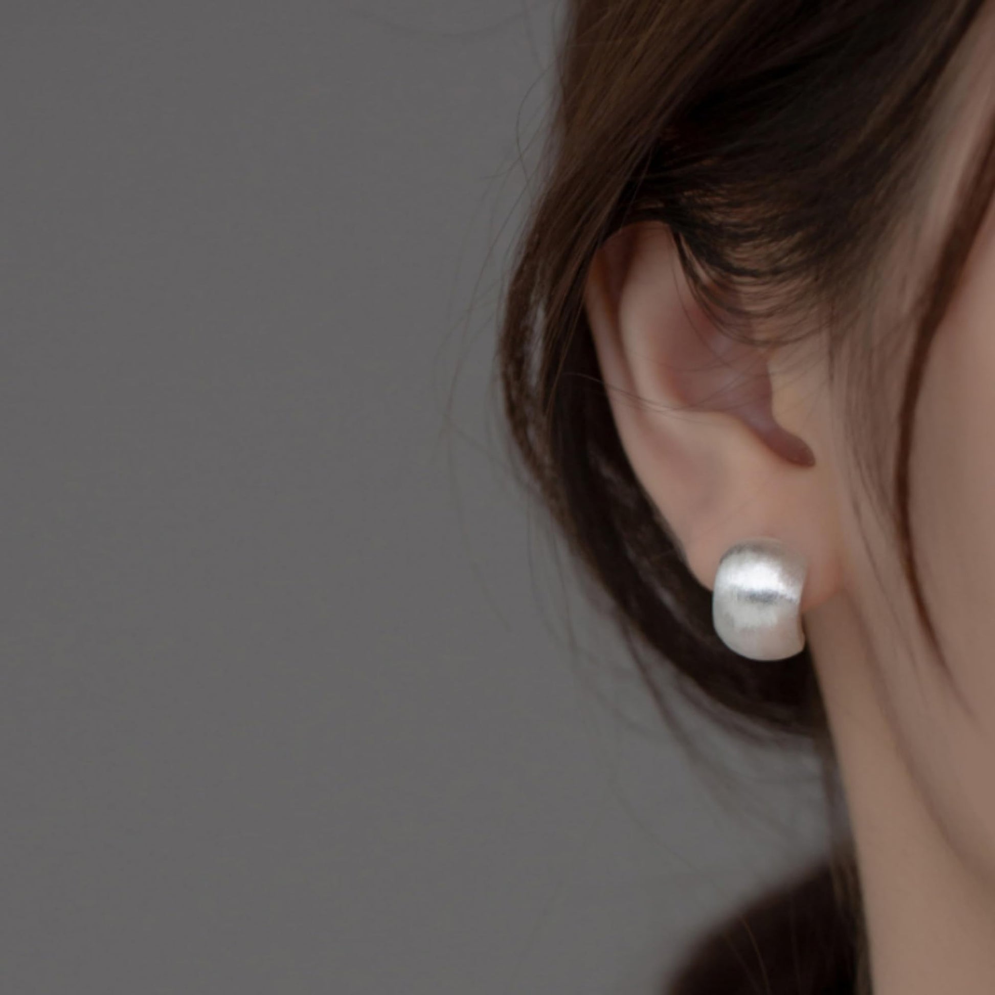 Brushed half-hoop drop earrings worn, silver half-hoop profile on earlobe