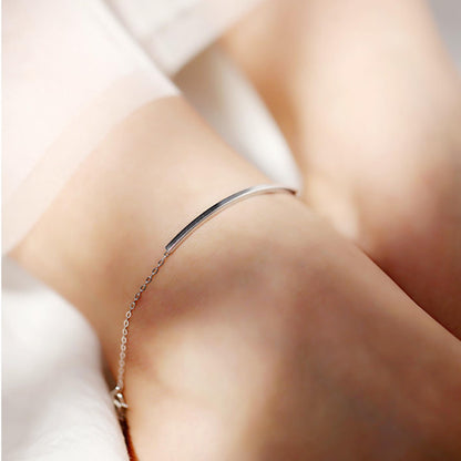 Curved Tube Curb Anklet worn on ankle: silver-tone curb chain with curved tube bar