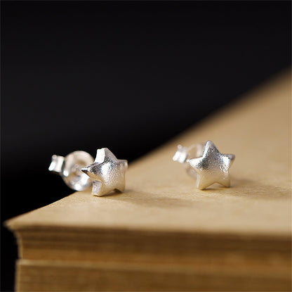 Puffy Star Studs auf Holzunterlage: silberfarbene Stern-Ohrstecker