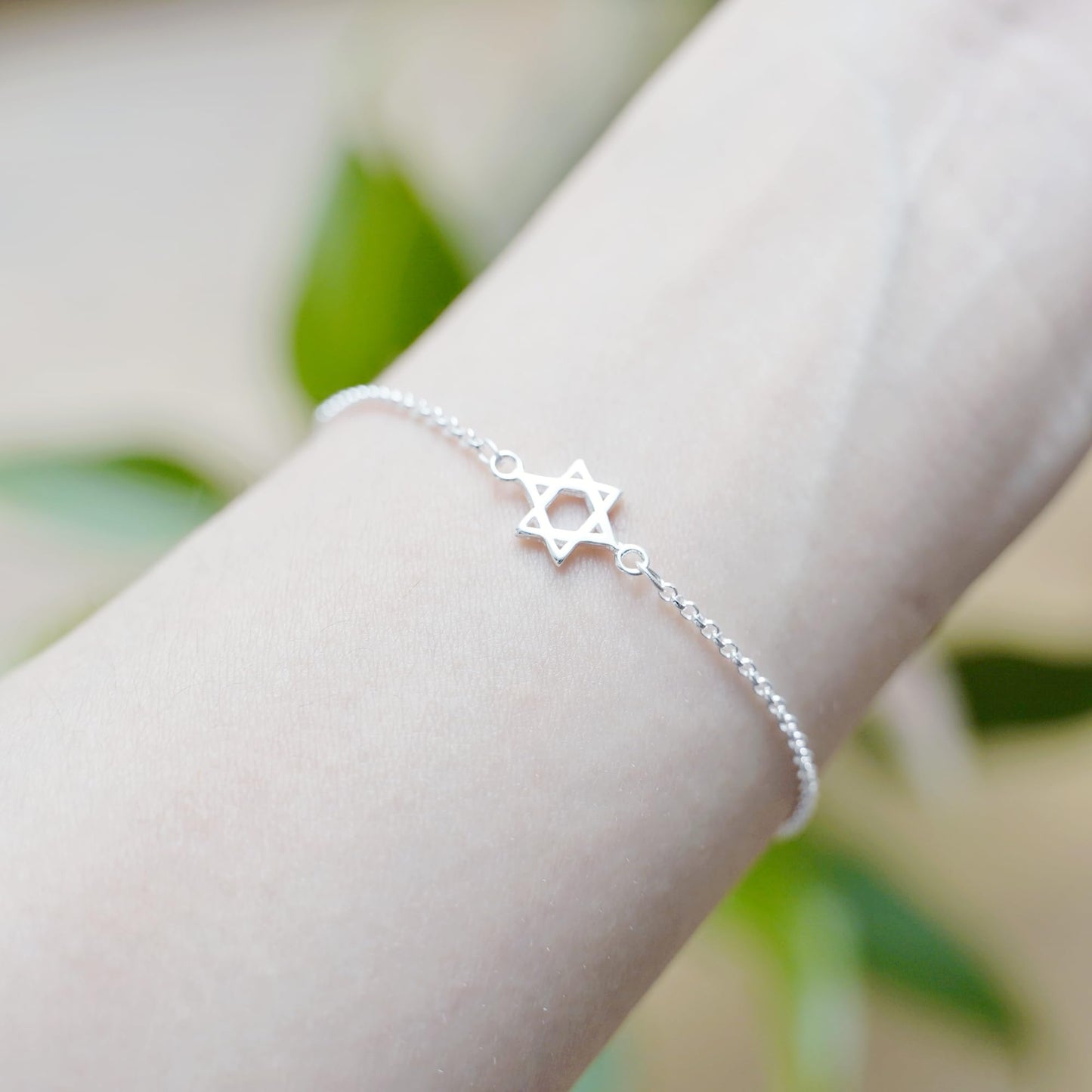Silver Star of David bracelet worn on wrist with star charm on chain.