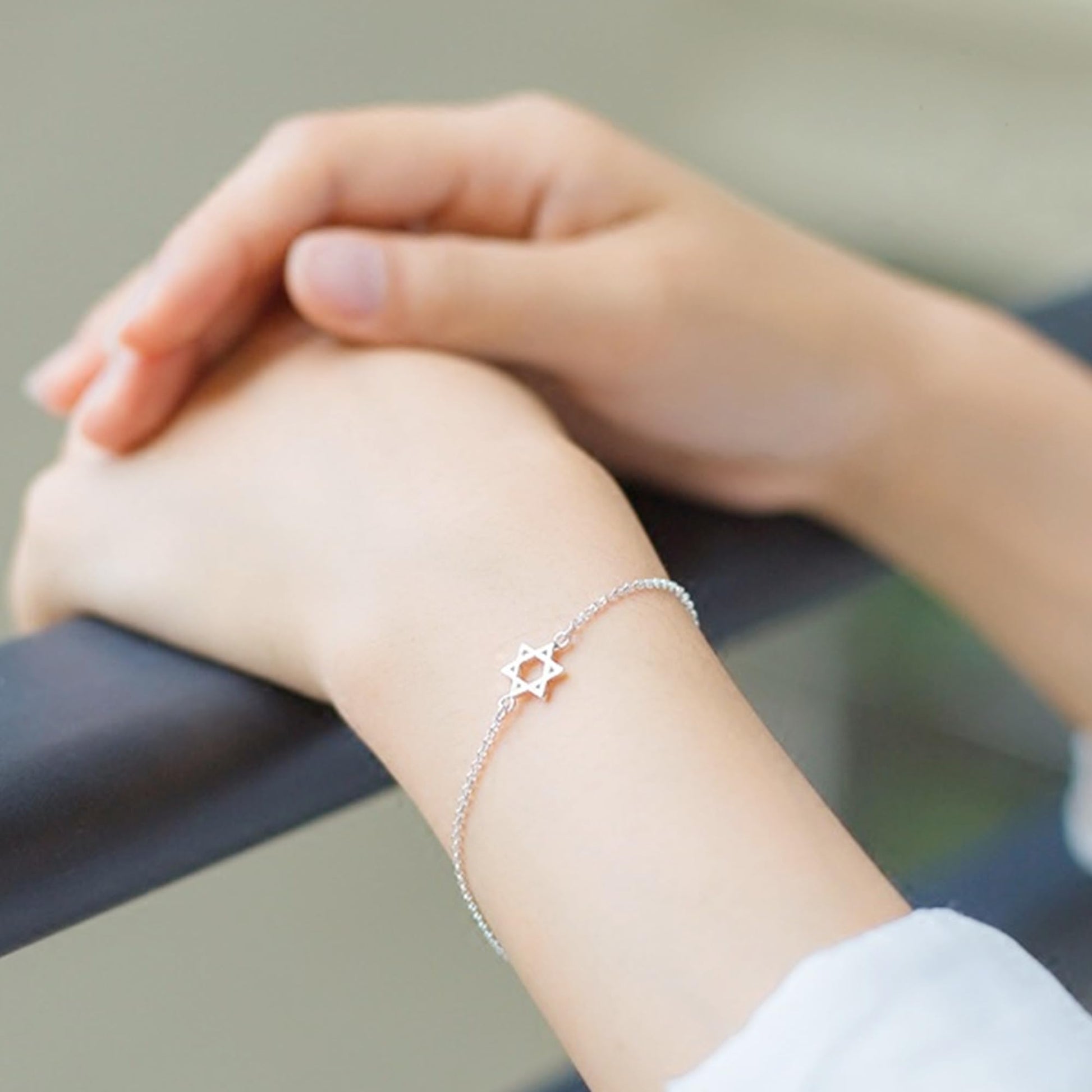 Silver Star of David bracelet on wrist with star charm at center.