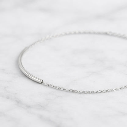 Curved Tube Curb Anklet close-up: curved tube bar with chain links and clasp
