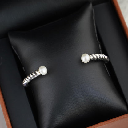 Pearl Twisted Torque Bangle on black display: pearl tips on twisted silver wire