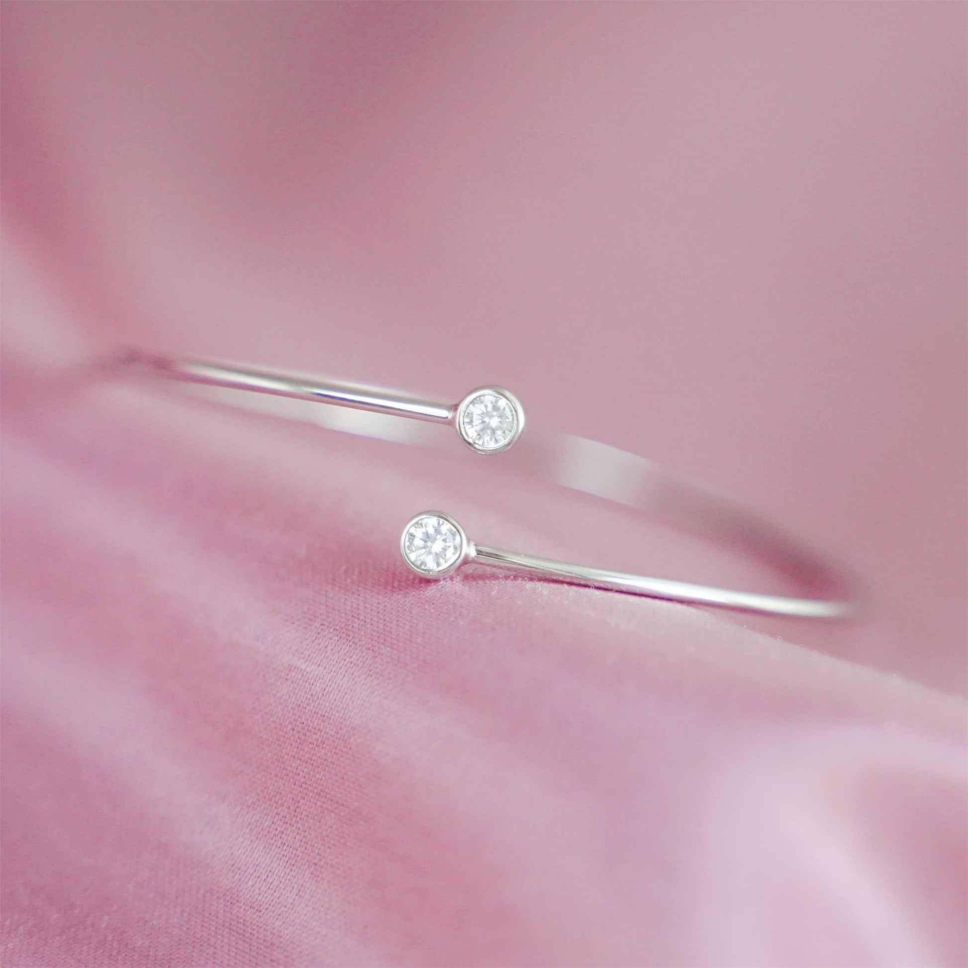 Close-up of silver CZ torque bangle with round bezel-set stones