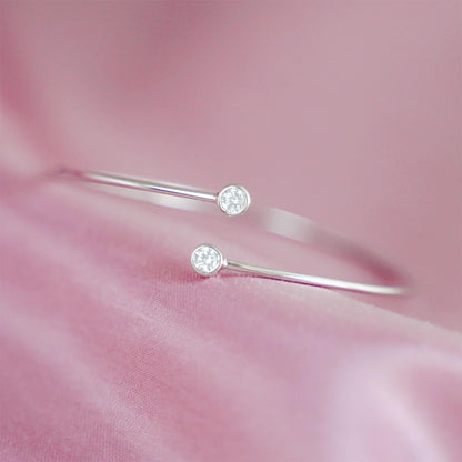Close-up of silver CZ torque bangle with round bezel-set stones