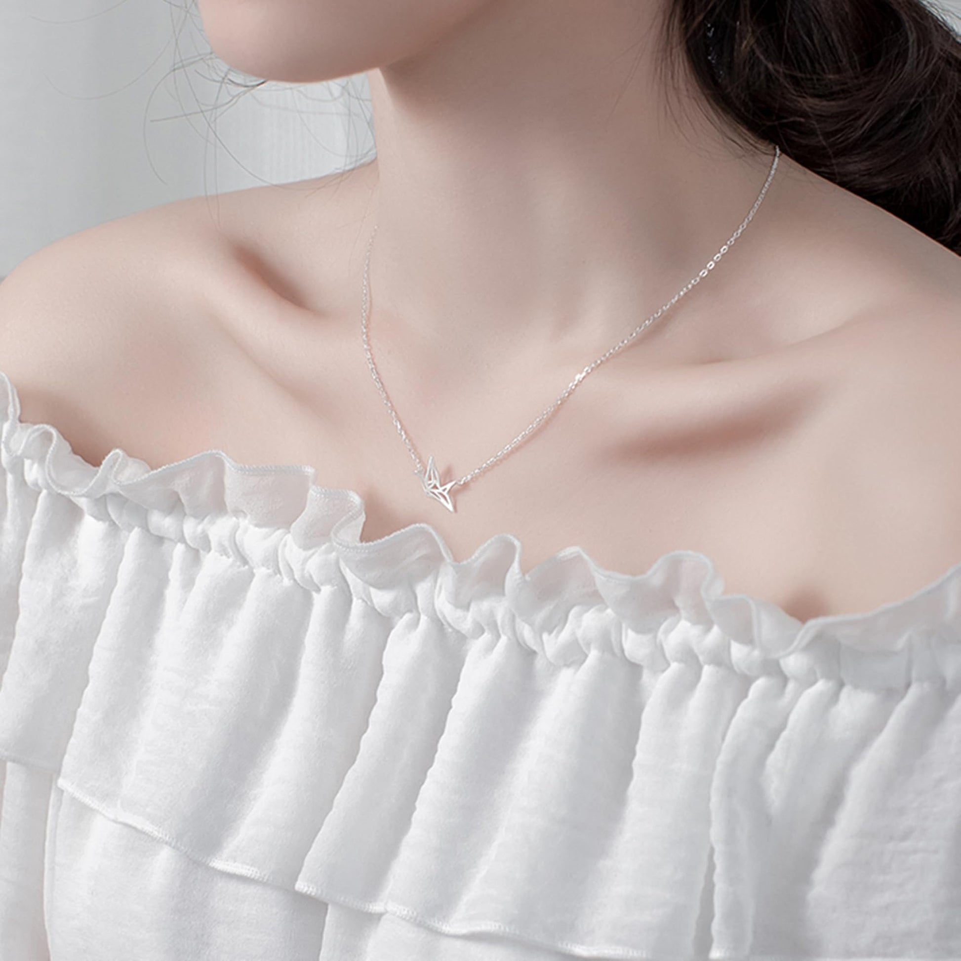 Origami crane necklace with silver chain and small crane pendant on chest