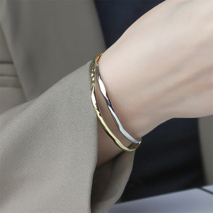 Hammered gold cuff bracelet on wrist, reflective curved surface